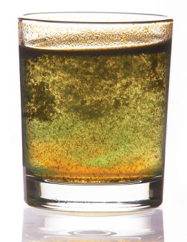 toxic water in glass with turbid sediment, yellow and green color. isolated on the white background